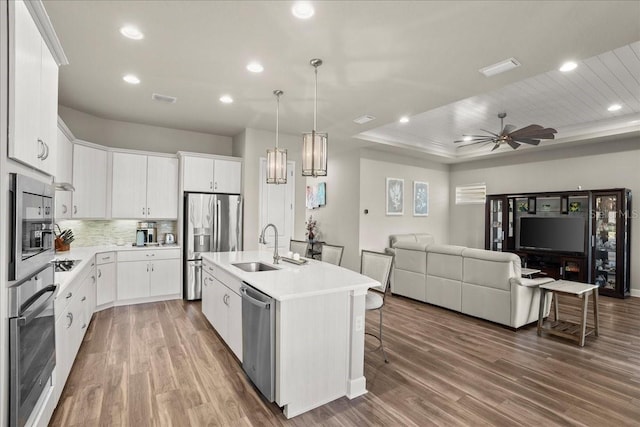 kitchen with ceiling fan, sink, a kitchen island with sink, white cabinets, and appliances with stainless steel finishes