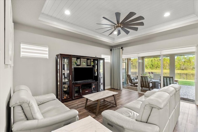 living room with ceiling fan, crown molding, hardwood / wood-style floors, a tray ceiling, and wood ceiling