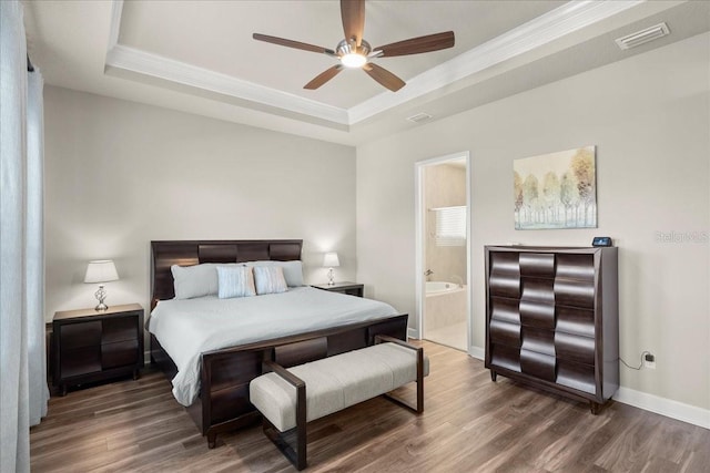 bedroom with ensuite bath, ceiling fan, dark hardwood / wood-style flooring, and a tray ceiling