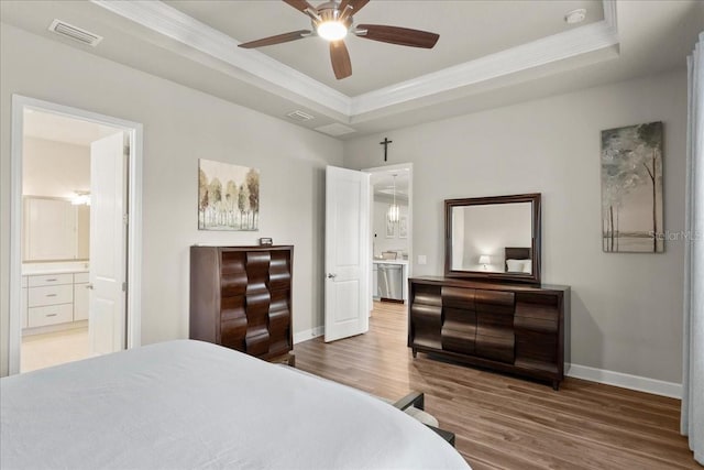 bedroom featuring ensuite bathroom, ornamental molding, a tray ceiling, ceiling fan, and hardwood / wood-style floors