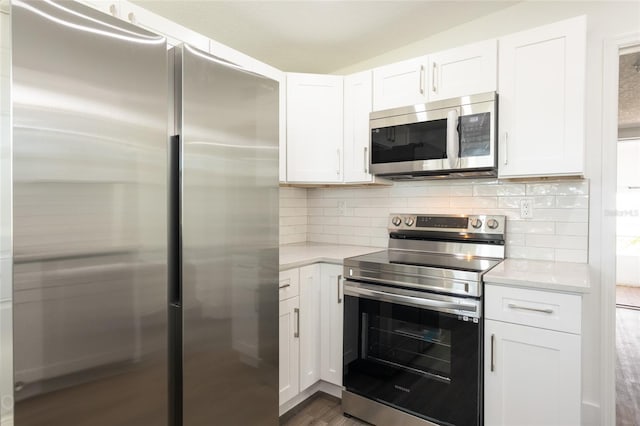 kitchen featuring white cabinetry, stainless steel appliances, light stone counters, dark hardwood / wood-style flooring, and backsplash