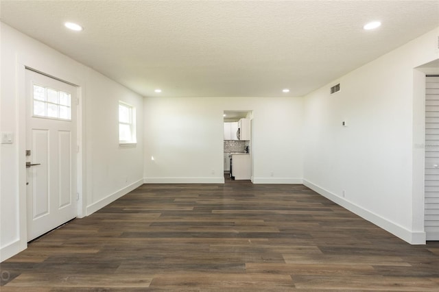 foyer entrance featuring a textured ceiling and dark wood-type flooring