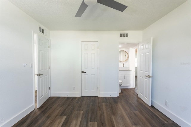 unfurnished bedroom featuring ensuite bath, ceiling fan, dark hardwood / wood-style floors, a textured ceiling, and a closet