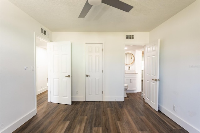 unfurnished bedroom featuring ensuite bathroom, a textured ceiling, ceiling fan, dark hardwood / wood-style floors, and a closet