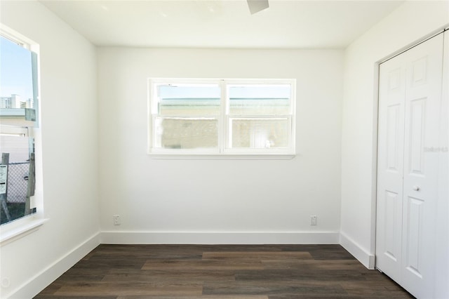 unfurnished bedroom featuring multiple windows, a closet, and dark wood-type flooring