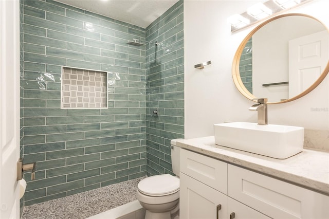 bathroom with vanity, toilet, and tiled shower