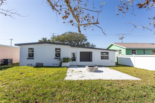 back of house featuring cooling unit, an outdoor fire pit, a patio area, and a lawn