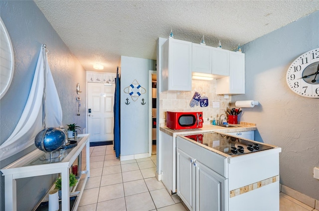 kitchen featuring light tile patterned floors, a textured ceiling, tasteful backsplash, and white cabinetry