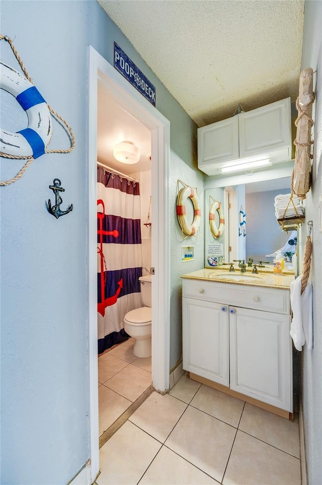 bathroom featuring tile patterned flooring, a textured ceiling, vanity, and toilet