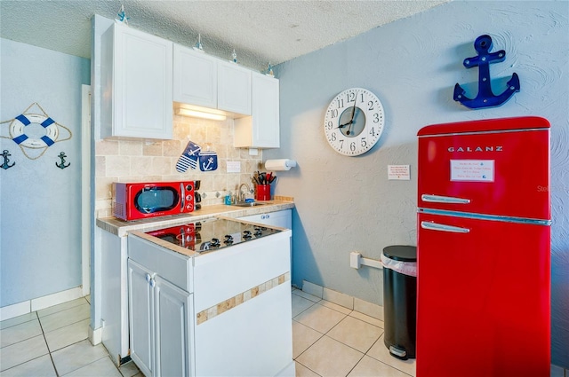 kitchen with sink, light tile patterned floors, tasteful backsplash, a textured ceiling, and white cabinets