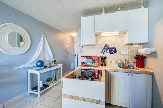 kitchen featuring backsplash, sink, white cabinets, and light tile patterned floors