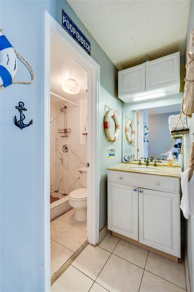 bathroom with vanity, tile patterned flooring, toilet, a textured ceiling, and a tile shower