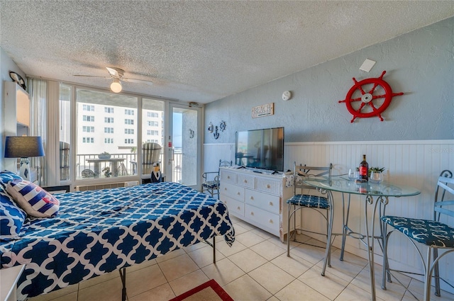 bedroom with ceiling fan, light tile patterned floors, and a textured ceiling