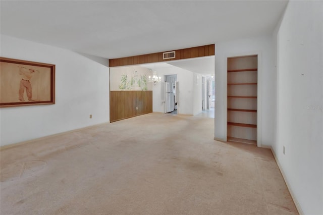 spare room featuring light colored carpet and an inviting chandelier