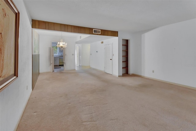 carpeted empty room with a chandelier