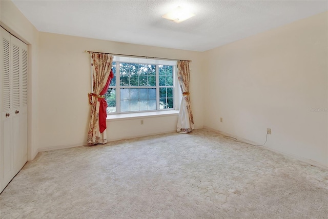 unfurnished bedroom featuring light carpet, a closet, and a textured ceiling