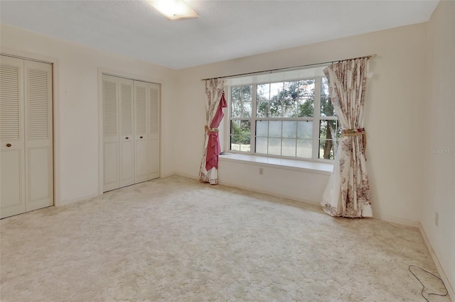 unfurnished bedroom with multiple closets, carpet, and a textured ceiling