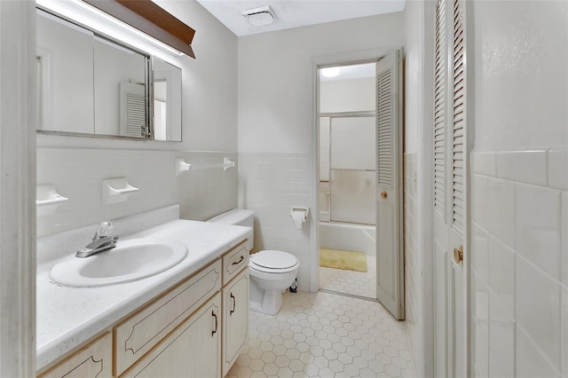 full bathroom with vanity, tile patterned flooring, toilet, enclosed tub / shower combo, and tile walls