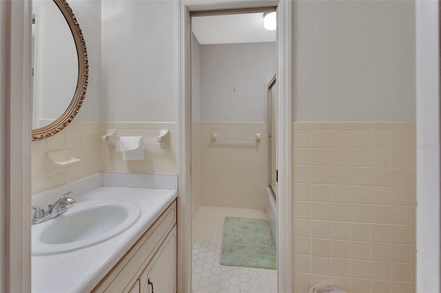 bathroom featuring vanity, an enclosed shower, and tile walls