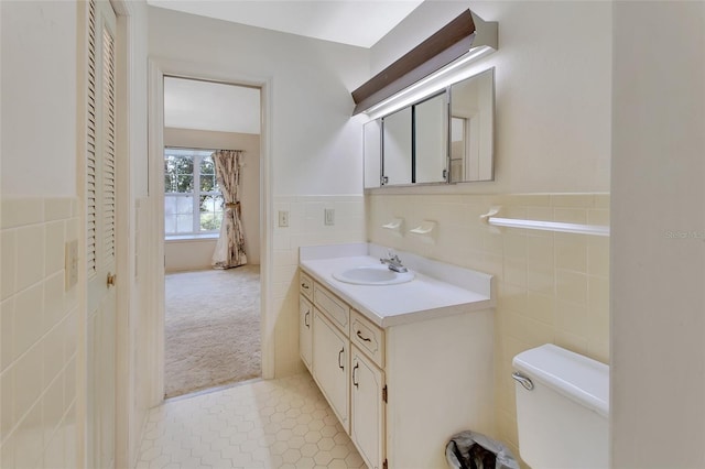 bathroom featuring tile patterned flooring, vanity, tile walls, and toilet