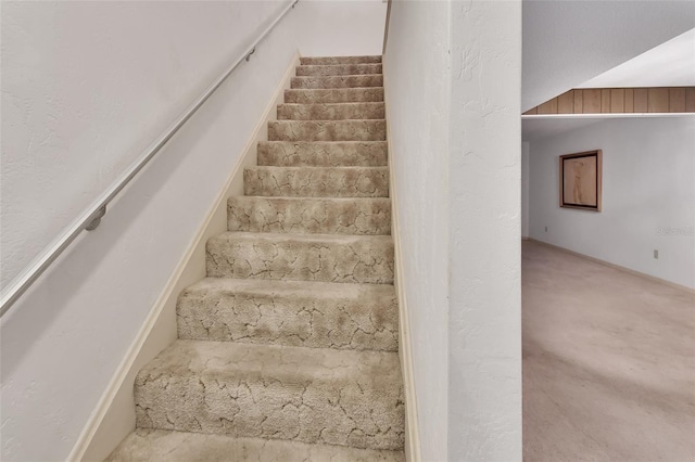 stairway featuring carpet floors and vaulted ceiling