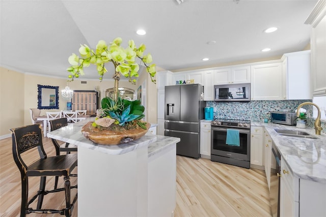 kitchen with white cabinets, sink, tasteful backsplash, a kitchen island, and stainless steel appliances