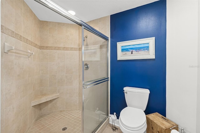 bathroom featuring a shower with door and toilet