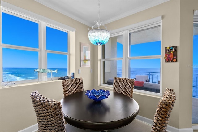 dining room with a chandelier, a water view, and ornamental molding