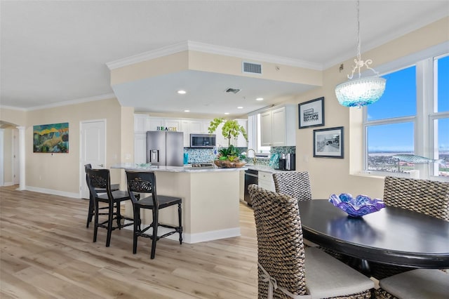 interior space with sink, light wood-type flooring, crown molding, and an inviting chandelier