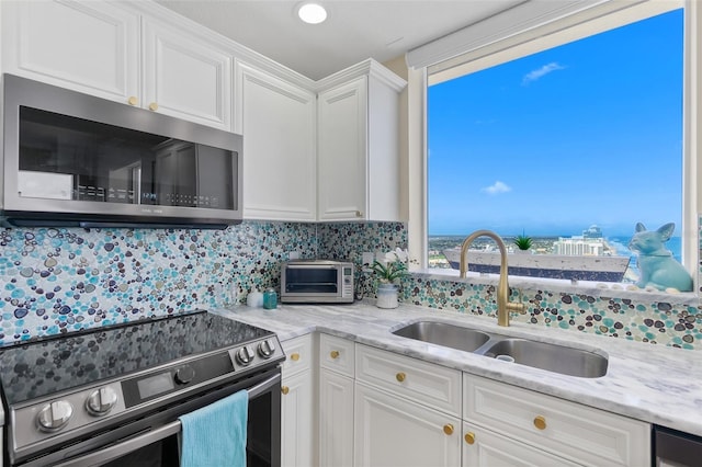 kitchen featuring light stone countertops, white cabinetry, sink, stainless steel appliances, and decorative backsplash