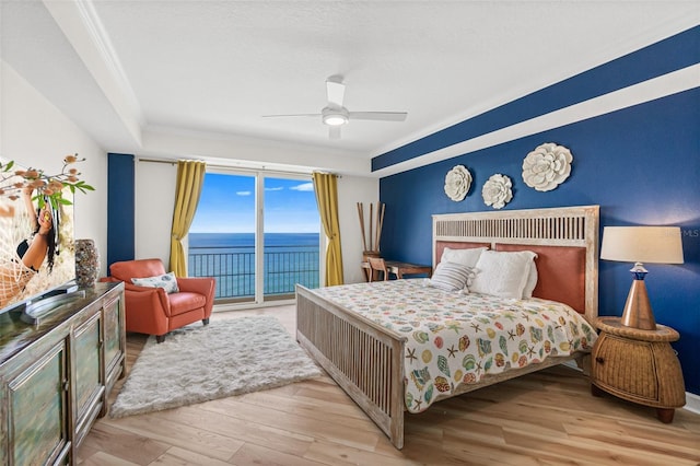 bedroom with access to exterior, ceiling fan, crown molding, a water view, and light wood-type flooring