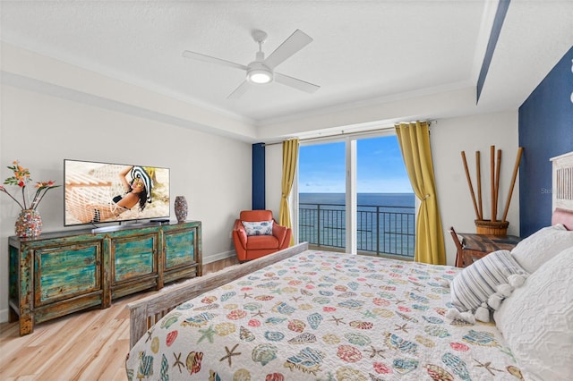 bedroom featuring ornamental molding, access to outside, a raised ceiling, ceiling fan, and wood-type flooring