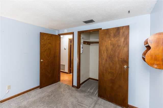 unfurnished bedroom featuring carpet floors, a textured ceiling, and a closet