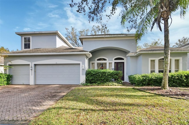 view of front of home featuring a garage, a front lawn, decorative driveway, and stucco siding