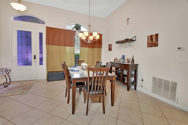 dining space with light tile patterned flooring, a towering ceiling, and an inviting chandelier