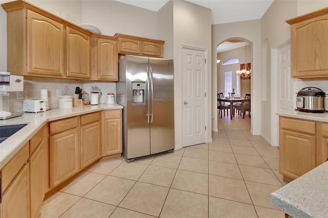 kitchen with backsplash, light brown cabinetry, light tile patterned floors, and stainless steel refrigerator with ice dispenser