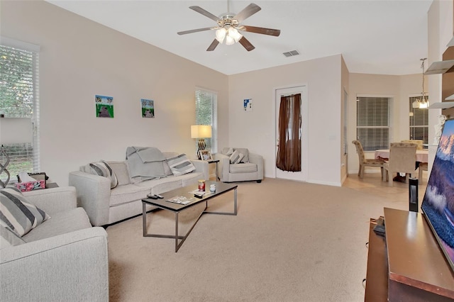 living room featuring a wealth of natural light, carpet, and ceiling fan with notable chandelier