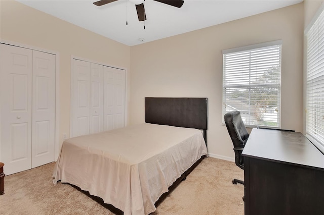 carpeted bedroom featuring ceiling fan and multiple closets