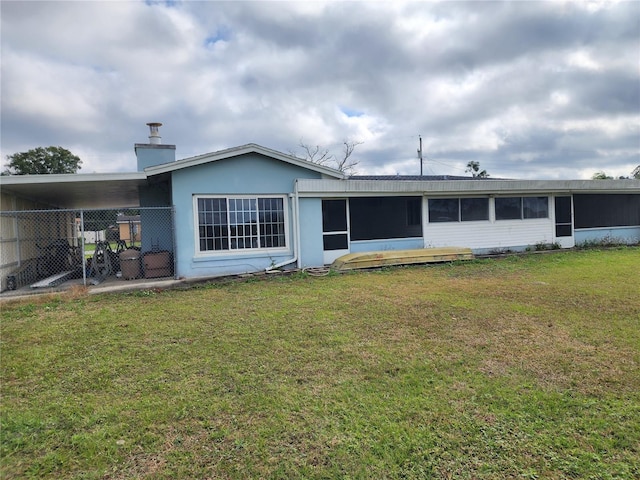 rear view of property with a carport and a lawn