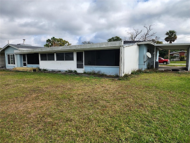 view of front of home with a front lawn, a carport, and a sunroom