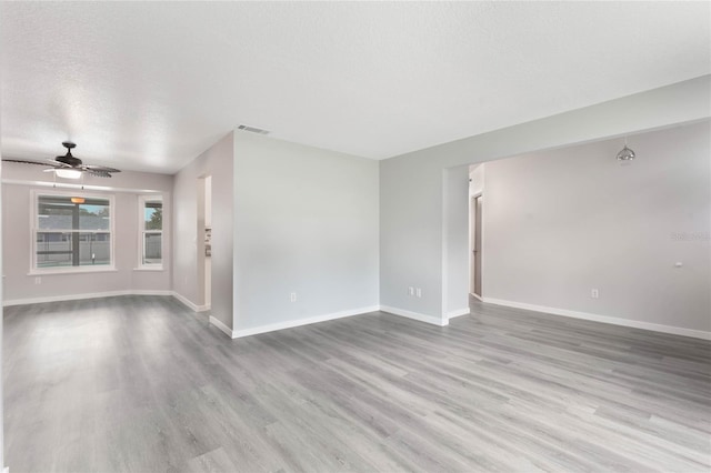 empty room with a textured ceiling, light hardwood / wood-style flooring, and ceiling fan