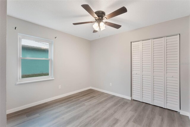 unfurnished bedroom featuring ceiling fan, light wood-type flooring, and a closet