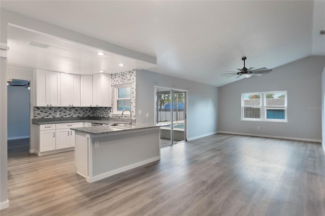 kitchen featuring backsplash, ceiling fan, sink, white cabinets, and lofted ceiling