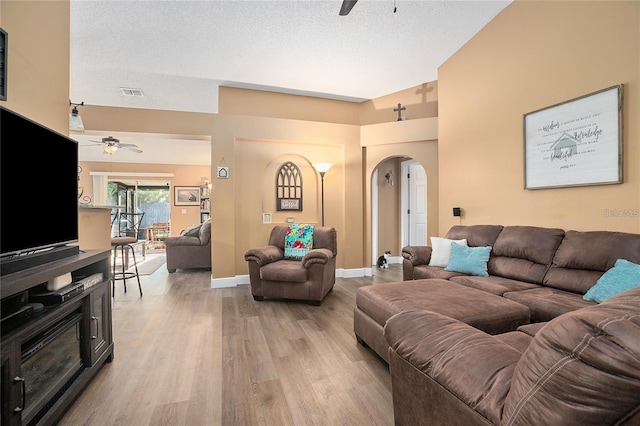 living room with wood-type flooring, a textured ceiling, and ceiling fan