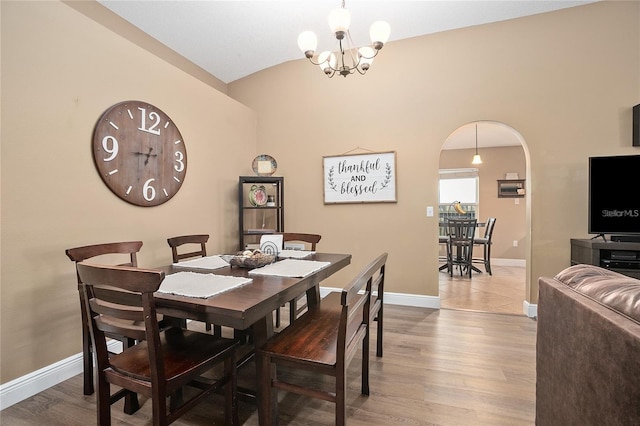 dining room featuring hardwood / wood-style floors, lofted ceiling, and a notable chandelier