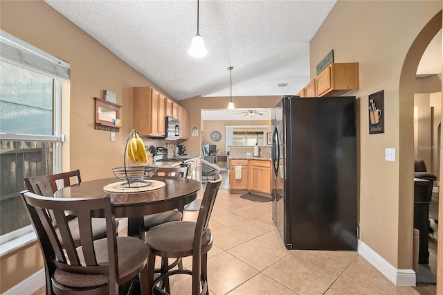 dining area with a textured ceiling, ceiling fan, light tile patterned floors, and vaulted ceiling