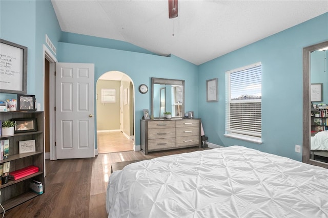 bedroom with a textured ceiling, ceiling fan, dark wood-type flooring, and vaulted ceiling