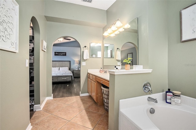 bathroom with tile patterned flooring, vanity, and tiled tub