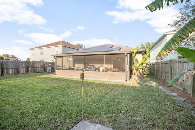 rear view of house featuring a sunroom, solar panels, a yard, and central air condition unit