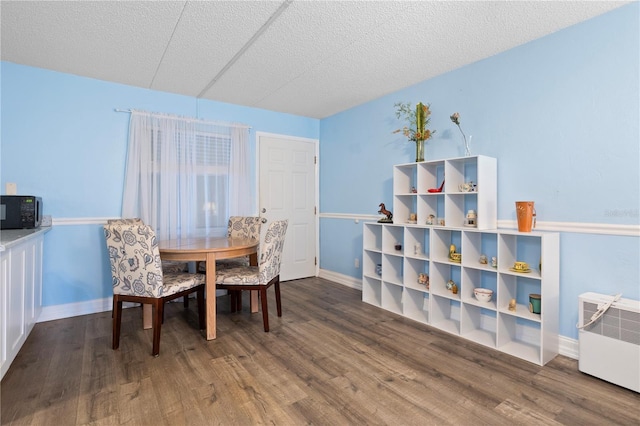 dining area featuring heating unit, dark hardwood / wood-style flooring, radiator heating unit, and a textured ceiling